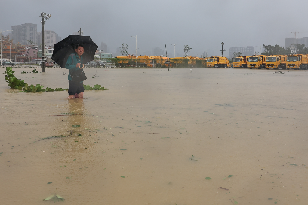 A person wades through the floodwaters to work after Typhoon Krathon made landfall in Taiwan