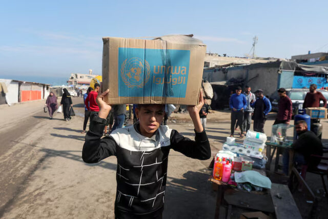 RIEUGQRMXRMMVFD6GL7KYKQEVE A Palestinian carries an aid box distributed by the United Nations Relief and Works Agency (UNRWA), amid the Israel-Hamas conflict, in Deir Al-Balah, central Gaza Strip, November 4, 2024. REUTERS/Ramadan Abed/File Photo