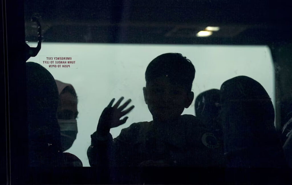 A day after U.S. forces completed their troop withdrawal from Afghanistan, an Afghan boy waves from a bus taking refugees to a processing center upon their arrival at Dulles International Airport in Dulles, Virginia, U.S., September 1, 2021. REUTERS/Kevin Lamarque/File Photo