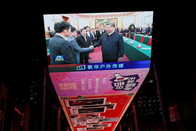 W2BZFQS23FPM3ETFXIVI3RY4JM A giant screen shows news footage of Chinese President Xi Jinping shaking hands with DeepSeek founder Liang Wenfeng during a symposium on private enterprises, at a shopping complex in Beijing, China, February 17, 2025. REUTERS/Florence Lo