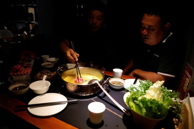 IAHT76QIYBORPGQB23F5SYIP54 A customer places beef meat imported from the U.S. into a hotpot while having dinner at the Jingli restaurant, in Beijing, China September 23, 2021. REUTERS/Carlos Garcia Rawlins/File Photo