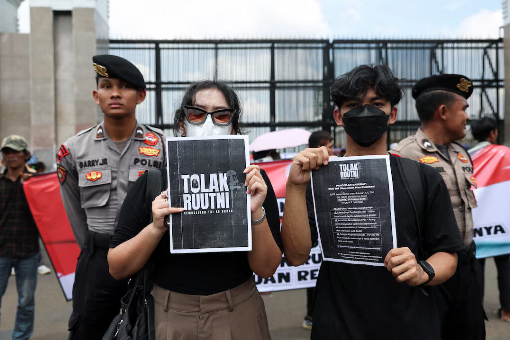 People hold posters as they protest outside the Indonesian parliament against a controversial military bill which will allocate more civilian posts for military officers, in Jakarta, Indonesia, March 20, 2025. REUTERS/Ajeng Dinar Ulfiana