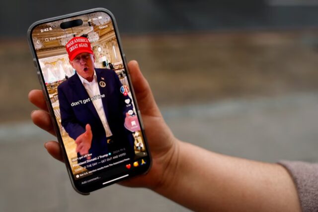 Y7G6PNXSJ5MFHAPIXJF3DO7XHM A woman poses with her smartphone displaying the @realdonaldtrump TikTok page, in Washington, U.S. January 19, 2025. REUTERS/Shannon Stapleton/File Photo
