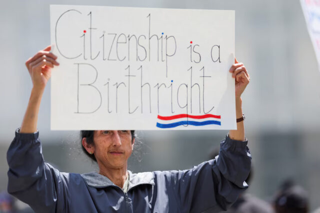 L3NLNXY2YRIBFB4I46DFG2UDYU Tanjam Jacobson holds a placard, as people protest on the day Supreme Court justices hear oral arguments over U.S. President Donald Trump's bid to broadly enforce his executive order to restrict automatic birthright citizenship, outside the U.S. Supreme Court in Washington, D.C., U.S., May 15, 2025. REUTERS/Leah Millis