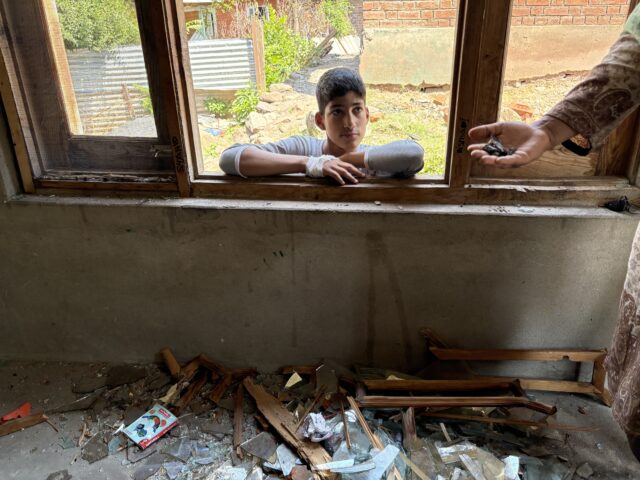 Zubina Begum, 45, a housewife showing shrapnels that lie scattered in her bedroom as her son, a Class X student, looks on