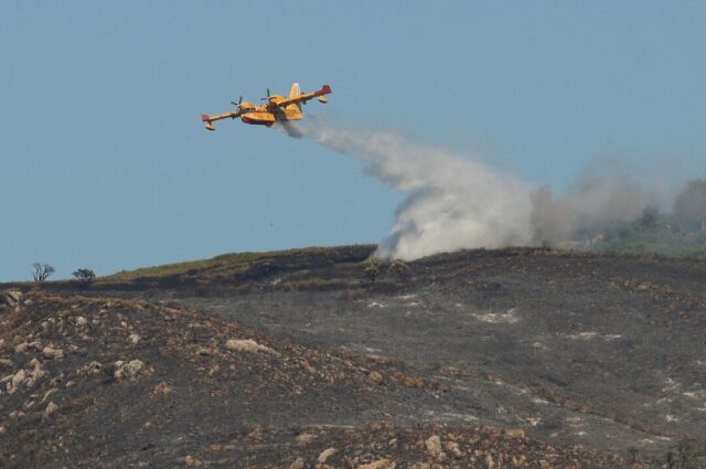 DHE5I4GDTZPOFFJCSFTDSPIXJY An aircraft makes a water drop over an area burned by a wildfire in the Atlanterra area in Tarifa, Spain, August 12, 2025. REUTERS/Marcelo Del Pozo