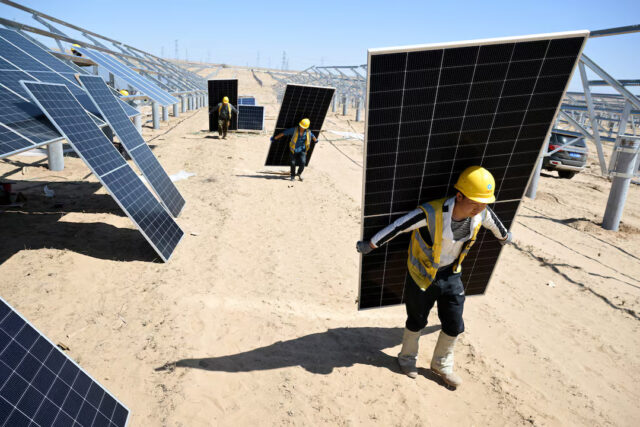 KDY3EBWFCJIF7OY3ZUV2FEMP4Y Workers carry solar panels to install them at a solar farm in the desert, in Lingwu, Ningxia Hui Autonomous Region, China April 14, 2025. China Daily via REUTERS/File Photo