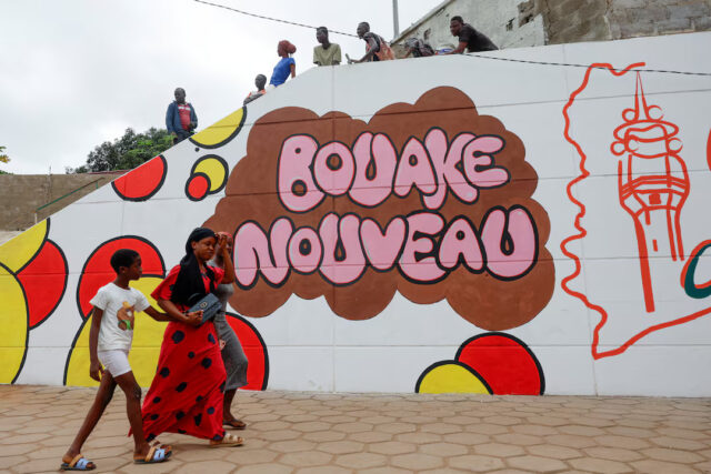 MCLBPNSO3ZO7JBCE2KEL2GW7FU Residents of Bouake walk past a painted wall, one day ahead of Ivory Coast 65th independence anniversary day in Bouake, Ivory Coast August 6, 2025. The painting on the wall reads "New Bouake" REUTERS/Luc Gnago/File Photo