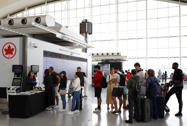 MUAJIG4KBNJVNLU7MFZYJ2ZVLI An Air Canada worker stands at a kiosk surrounded by passengers at Toronto Pearson International Airport, following the end of the Air Canada labour strike, in Mississauga, Ontario, Canada, August 19, 2025. REUTERS/Wa Lone