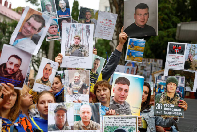 ZIR6KLRMLZM7LACSU4RZN43TG4 (1) People hold portraits of their relatives, Ukrainian prisoners of war (POWs), hoping they will be recognized by other prisoners of war, who return after a swap, amid Russia's attack on Ukraine, in an undisclosed location, in Ukraine August 24, 2025. REUTERS/Valentyn Ogirenko