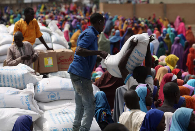 3O72KGUVNBJYZLUE2HYXYLI5Z4 Camp workers offload sorghum at open field as beneficiaries from different Internally Displaced Persons camps wait to receive support following the exit of USAID, at a World Food Programme distribution centre in Dikwa, Borno State, Nigeria, August 27, 2025. REUTERS/Sodiq Adelakun.