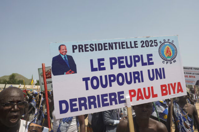 P72QEKSY45LZZCHXPMHZG7NCDE Supporters of Cameroon's 92-year-old President Paul Biya, who is seeking an eighth term, hold a sign during the launch of his electoral campaign, in Maroua, Cameroon, October 7, 2025. The sign reads "The Toupouri people united behind Biya". REUTERS/Desire Danga Essigue