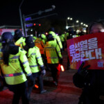 A woman holds a placard as police officers walk outside the National Assembly, after South Korean President Yoon Suk Yeol declared martial law, in Seoul, South Korea, December 4, 2024. REUTERS/Kim Hong-Ji