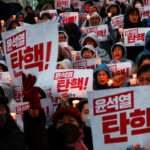 People hold candles and signs during a candlelight vigil to demand the resignation of South Korean President Yoon Suk Yeol, who declared martial law which was reversed hours later, at the National Assembly in Seoul, South Korea, December 5, 2024. REUTERS/Kim Hong-ji
