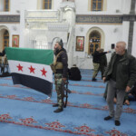 Rebel fighters hold a Syrian opposition flag in Homs after Syria's army command notified officers on Sunday that President Bashar al-Assad's 24-year authoritarian rule has ended, a Syrian officer who was informed of the move told Reuters, following a rapid rebel offensive that took the world by surprise, in Homs, Syria December 8, 2024. REUTERS/Mahmoud Hasano