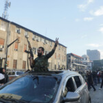 A rebel fighter gestures from a vehicle as they gather in Homs after Syria's army command notified officers on Sunday that President Bashar al-Assad's 24-year authoritarian rule has ended, a Syrian officer who was informed of the move told Reuters, following a rapid rebel offensive, in Homs, Syria December 8, 2024. REUTERS/Mahmoud Hasano