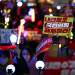 A protester holds a sign that reads "Disassemble ruling People Power Party cooperating rebellion" during a rally calling for the impeachment of South Korean President Yoon Suk Yeol, who declared martial law, which was reversed hours later, in front of the National Assembly in Seoul, South Korea, December 10, 2024. REUTERS/Kim Hong-Ji