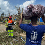 A man carries his belongings as rescue workers attempt to clear a blocked road, in the aftermath of Cyclone Chido, within Labattoir, in Mayotte, France, December 15, 2024. REUTERS/Chafion Madi