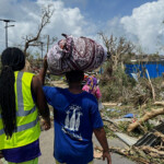 A man carries his belongings as rescue workers attempt to clear a blocked road, in the aftermath of Cyclone Chido, within Labattoir, in Mayotte, France, December 15, 2024. REUTERS/Chafion Madi