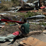 A boy sits near the ruins of homes, in the aftermath of Cyclone Chido, within Labattoir, in Mayotte, France, December 15, 2024. REUTERS/Chafion Madi