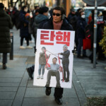 A man walks carrying a poster as protesters rally against the impeached South Korean President Yoon Suk Yeol near his official residence, after investigators were unable to execute an arrest warrant on Friday for Yoon, according to the Corruption Investigation Office for High-ranking Officials, in Seoul, South Korea, January 3, 2025. REUTERS/Kim Hong-Ji