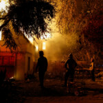 Firefighters stand near a burning house, as powerful winds fueling devastating wildfires in the Los Angeles area force people to evacuate, at the Eaton Fire in Altadena, California, U.S. January 8, 2025. REUTERS/Fred Greaves