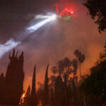 A helicopter flies, as smoke and flames rise from the Sunset Fire in the hills overlooking the Hollywood neighborhood of Los Angeles, California, U.S. January 8, 2025. REUTERS/David Swanson