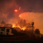 A helicopter performs a water drop, as smoke and flames rise from the Sunset Fire in the hills overlooking the Hollywood neighborhood of Los Angeles, California, U.S. January 8, 2025. REUTERS/David Swanson