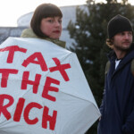 A demonstrator holds an umbrella with a message, as they attend an anti-WEF and climate activist protest, ahead of the opening of the World Economic Forum, in Davos, Switzerland January 19, 2025. REUTERS/Yves Herman