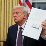 U.S. President Donald Trump holds a document on the day he issues executive orders and pardons for January 6 defendants in the Oval Office at the White House on Inauguration Day in Washington, U.S., January 20, 2025. REUTERS/Carlos Barria