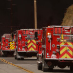 Fire trucks drive as smoke rises from the Hughes Fire near Castaic Lake, north of Santa Clarita, California, U.S. January 22, 2025. REUTERS/David Swanson