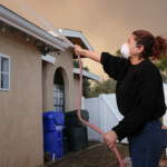 Tania Carbajal sprays down her home with water as the Hughes Fire burns in Castaic, California, U.S. January 22, 2025. REUTERS/Joel Angel Juarez