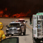 Law enforcement vehicles drive past flames rising from the Hughes Fire near Castaic Lake, north of Santa Clarita, California, U.S. January 22, 2025. REUTERS/David Swanson