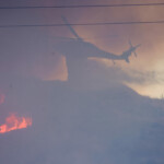 A helicopter drops water as the Hughes Fire burns in Castaic Lake, California, U.S. January 22, 2025. REUTERS/David Swanson