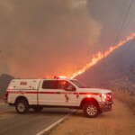 Flames rise in the background, behind an emergency services vehicle, as firefighters and aircraft battle the Hughes Fire near Castaic Lake, north of Santa Clarita, California, U.S. January 22, 2025. REUTERS/Ringo Chiu