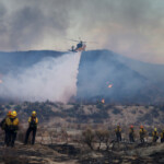 A helicopter drops water as the Hughes Fire burns in Castaic Lake, California, U.S. January 22, 2025. REUTERS/David Swanson