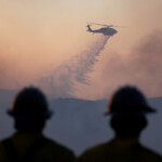 A helicopter drops water, as firefighters and aircraft battle the Hughes Fire near Castaic Lake, north of Santa Clarita, California, U.S. January 22, 2025. REUTERS/Ringo Chiu