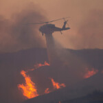 A helicopter drops water, as firefighters and aircraft battle the Hughes Fire near Castaic Lake, north of Santa Clarita, California, U.S. January 22, 2025. REUTERS/Ringo Chiu