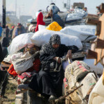 A woman sits as Palestinians, who were displaced to the south at Israel's order during the war, wait to head back to their homes in northern Gaza by vehicle through Salahudeen Road, amid a ceasefire between Israel and Hamas, in the central Gaza Strip, January 27, 2025. REUTERS/Hatem Khaled
