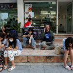 People sit in front of a shop after a strong earthquake struck central Myanmar on Friday, earthquake monitoring services said, which affected Bangkok as well with hundreds of people pouring out of buildings in the Thai capital in panic after the tremors, in Bangkok, Thailand, March 28, 2025. REUTERS/Chalinee Thirasupa