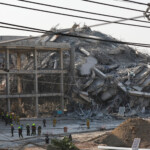 Rescue personnel stand near a building that collapsed after a strong earthquake struck central Myanmar on Friday, earthquake monitoring services said, which affected Bangkok as well with people pouring out of buildings in the Thai capital in panic after the tremors, in Bangkok, Thailand, March 28, 2025. REUTERS/Athit Perawongmetha