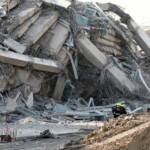 Rescue personnel stand near a building that collapsed after a strong earthquake struck central Myanmar on Friday, earthquake monitoring services said, which affected Bangkok as well with people pouring out of buildings in the Thai capital in panic after the tremors, in Bangkok, Thailand, March 28, 2025. REUTERS/Athit Perawongmetha