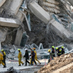 Rescue personnel walk near a building that collapsed after a strong earthquake struck central Myanmar on Friday, earthquake monitoring services said, which affected Bangkok as well with people pouring out of buildings in the Thai capital in panic after the tremors, in Bangkok, Thailand, March 28, 2025. REUTERS/Athit Perawongmetha