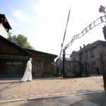 FILE PHOTO: Pope Francis walks through Auschwitz's notorious gate with the sign "Arbeit Macht Frei" (Work sets you free) during his visit to the former Nazi death camp, Poland, July 29, 2016. Filippo Monteforte/Pool via REUTERS/File Photo