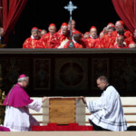 Clergy members kneel by the coffin of Pope Francis during his funeral Mass in St. Peter's Square at the Vatican, April 26, 2025. REUTERS/Guglielmo Mangiapane