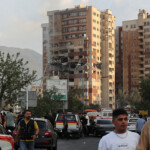 People walk near a damaged building in the aftermath of Israeli strikes, in Tehran, Iran, June 13, 2025. Majid Asgaripour/WANA (West Asia News Agency) via REUTERS