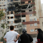 People look at a damaged building in the aftermath of Israeli strikes, in Tehran, Iran, June 13, 2025. Majid Asgaripour/WANA (West Asia News Agency) via REUTERS