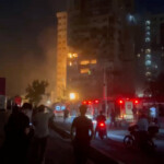 People watch as fire burns in a building damaged in an Israeli strike in Tehran, Iran in this screengrab obtained from a social media video released on July 13, 2025. Social Media/via REUTERS