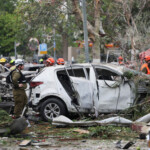 Rescue personnel stand next to damaged vehicles as they work at an impact site following missile attack from Iran on Israel, in Rishon LeZion, Israel, June 14, 2025. REUTERS/Ronen Zvulun