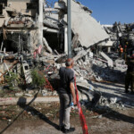 A man stands as rescue personnel work at an impact site following missile attack from Iran on Israel, in Rishon LeZion, Israel, June 14, 2025. REUTERS/Ronen Zvulun